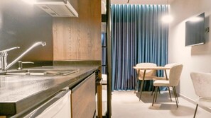 A modern kitchen with a sink and a dining area with a table and chairs. - Eden Hotel Spille (Rrogozhine)