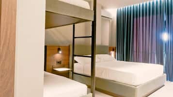 Habitación de hotel con literas, mesitas de noche y una cortina con diseño degradado.