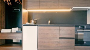 A modern kitchen with wooden cabinets, a built-in oven, and a refrigerator. - Eden Hotel Spille (Rrogozhine)