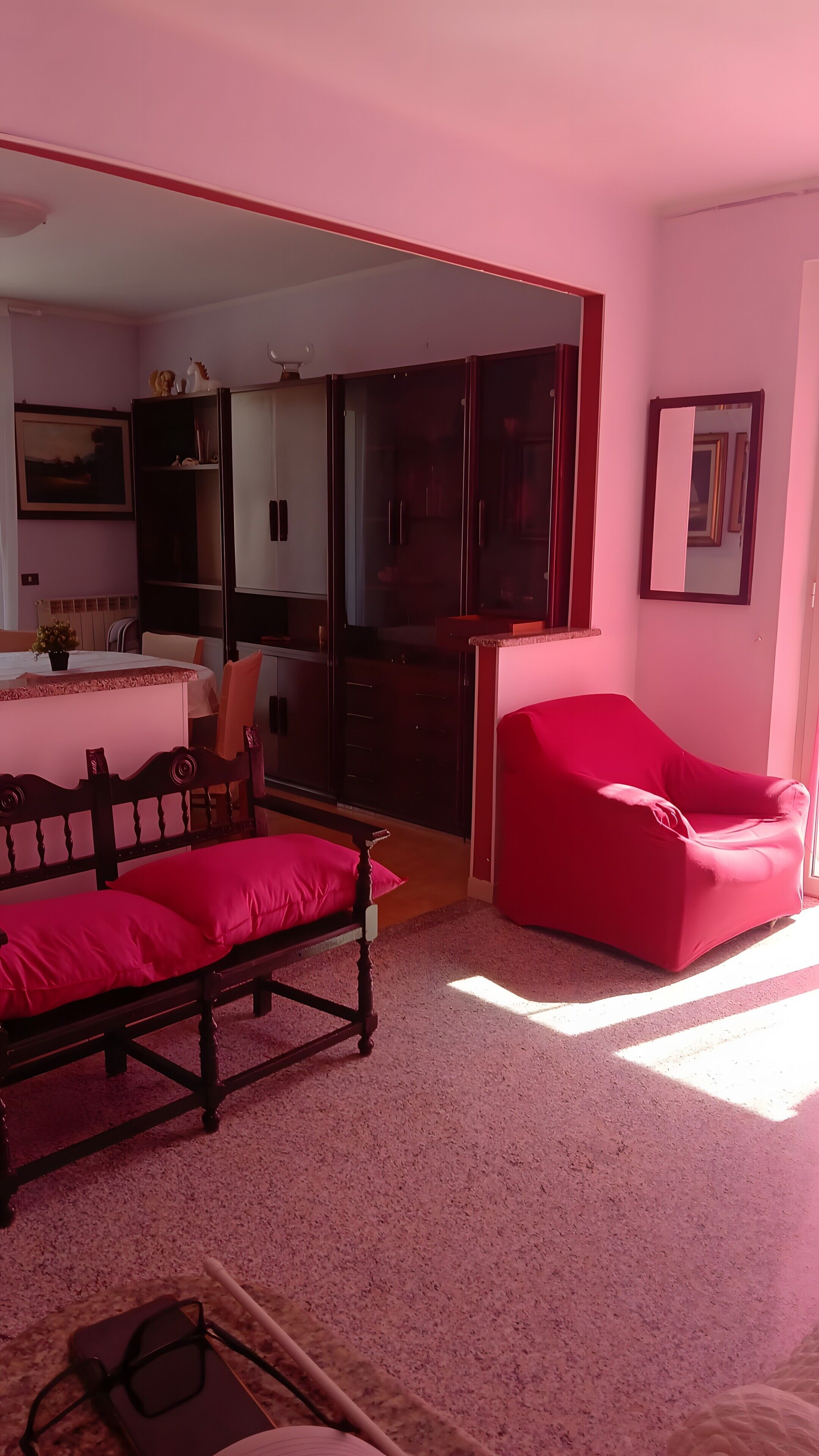 Ein Schlafzimmer mit einem Bett, einem roten Sessel, einer Kommode und einem Spiegel.