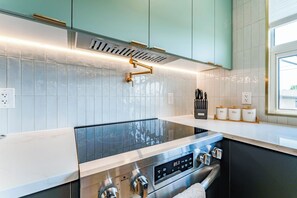 A modern kitchen with a stainless steel range, a built-in oven, and a window providing natural light. - Luxury Designer Home with Spa Bathrooms • King Bed • AC • Minutes to Downtown (Calgary)