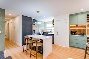 Una cocina moderna con una isla central, taburetes de bar, una estación de café y vistas de la ciudad.