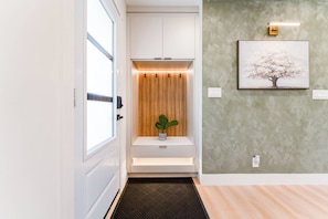 A modern hallway with a built-in bench, a wall-mounted light fixture, and a framed picture.