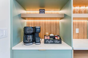 Um café com uma máquina de café Keurig, uma caneca e um recipiente para grãos de café.