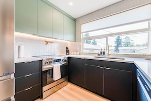 A modern kitchen with a built-in oven, a stovetop, and a window with a view of the outside.