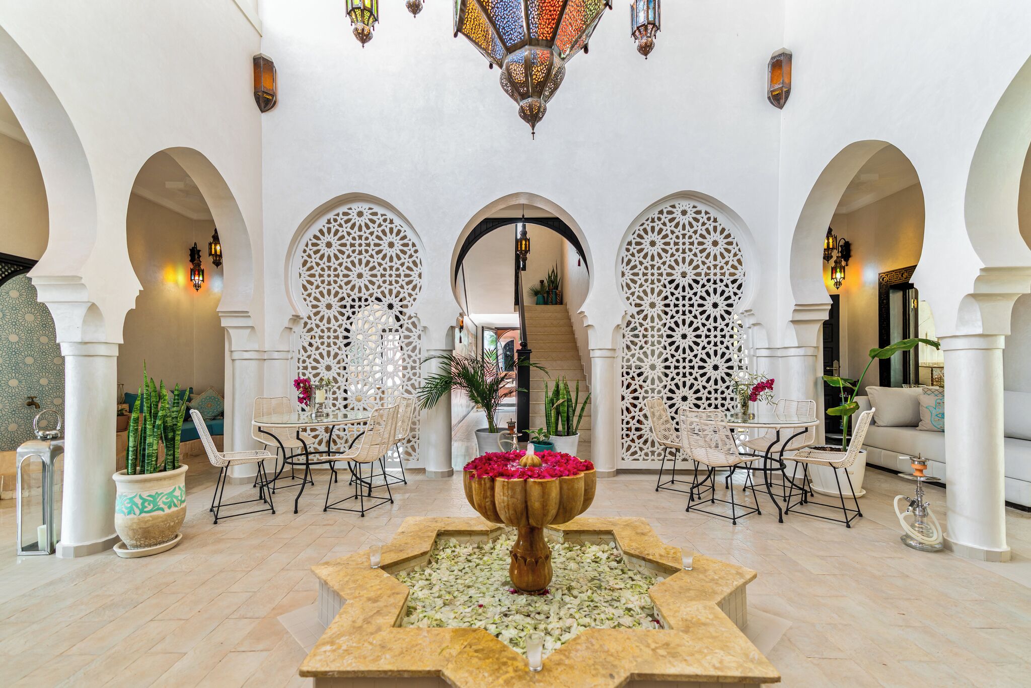 A spacious lobby with a central fountain, arched walkways, and seating areas.