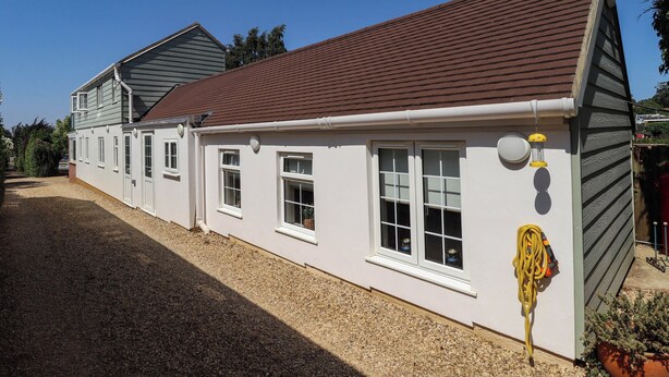 A two-story house with a gravel driveway and a red roof. - Bee Hive Hut (King's Lynn)