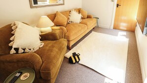 A living room with a sofa, a lamp, a remote control, and a rug. - Bee Hive Hut (King's Lynn)