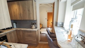 Una cocina moderna con encimeras de mármol, armarios de madera y una zona de bar con taburetes.