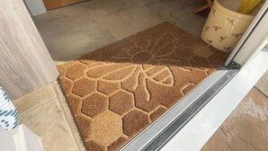 Un felpudo con estampado de hojas, una puerta de madera y un suelo de baldosas.