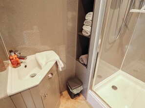 A bathroom with a sink, a mirror, a shower, and a towel rack.