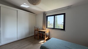 Een slaapkamer met een bed, een bureau en een raam.