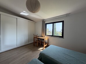 Ein Schlafzimmer mit Bett, Schreibtisch und Fenster.