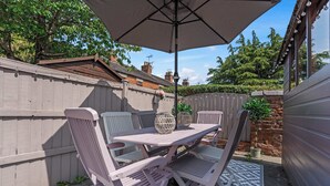 An outdoor patio with a table and chairs, an umbrella, and a patterned rug. - Charming 2-Bed Home Away from Home in Nantwich (Cheshire East)