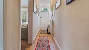A hallway with a floral carpet, a white door, and a radiator. - Charming 2-Bed Home Away from Home in Nantwich (Cheshire East)