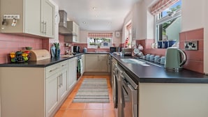 A modern kitchen with a central island, built-in appliances, and a view to the outside. - Charming 2-Bed Home Away from Home in Nantwich (Cheshire East)
