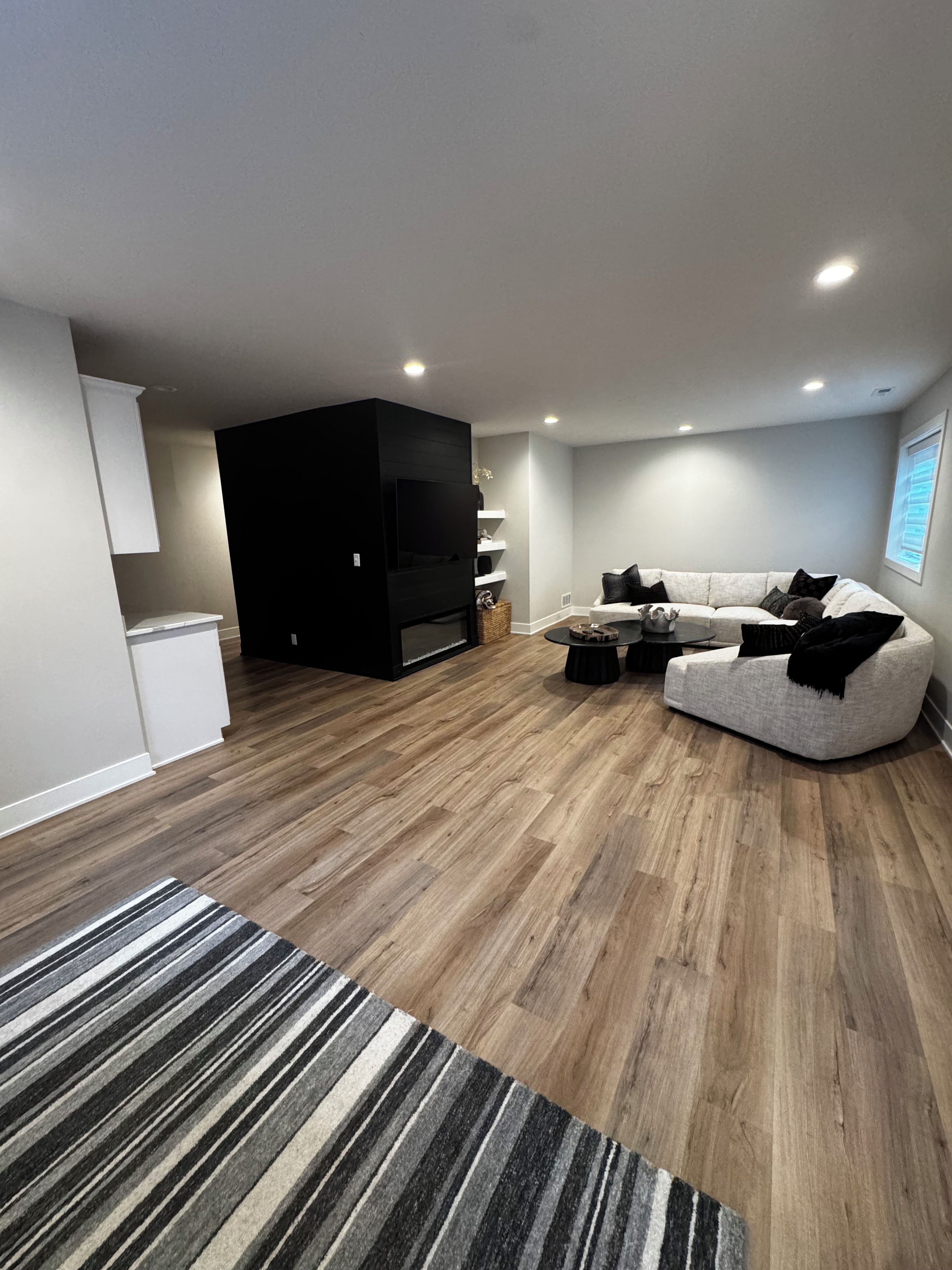 Una sala de estar moderna con un sofá seccional, un televisor de pantalla plana y piso de madera.