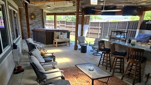 A covered outdoor patio with seating, a bar area, and a view of the backyard. - Spacious Lakefront Retreat House with 1100sqft Sports Bar Patio & Hot Tub Near Little Elm Beach, Little Elm, Texas (Little Elm)