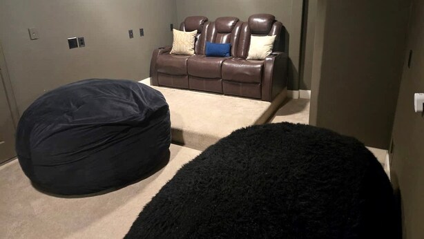 A room with a brown leather sofa, a black bean bag chair, and a fluffy black rug. - Spacious Lakefront Retreat House with 1100sqft Sports Bar Patio & Hot Tub Near Little Elm Beach, Little Elm, Texas (Little Elm)