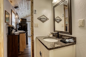 A bathroom with a large mirror, a sink, and a shower area.