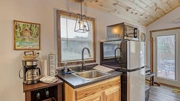 A compact kitchen with a sink, a coffee maker, and a refrigerator.