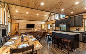 Interior espaçoso de uma cabana, com área de jantar, cozinha e sala de estar.