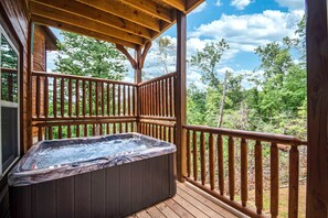 Uma banheira de hidromassagem em um deck de madeira com vista para árvores e céu.
