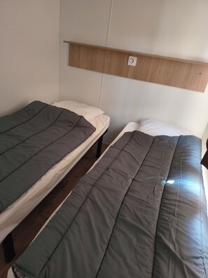 Two single beds with wooden headboards and a white wall.