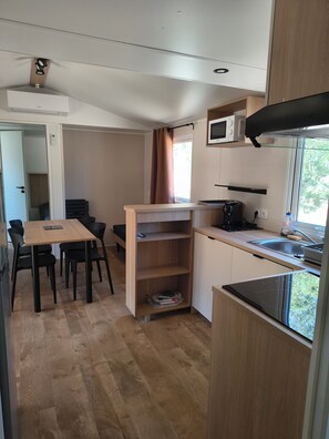 A compact kitchen with a dining area, a microwave, a stove, and a window with a view.