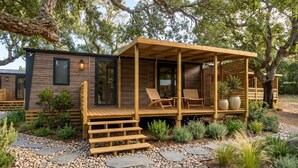 A wooden cabin with a porch, seating area, and potted plants.