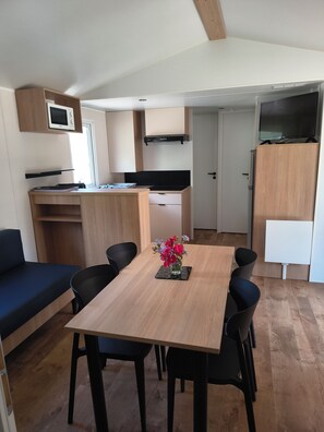 A compact living space with a kitchenette, a dining area with a table and chairs, and a sofa.