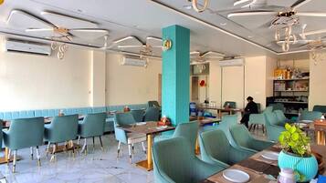Interior moderno de restaurante com piso de mármore, assentos estofados em tons de verde-água e ventiladores de teto contemporâneos.