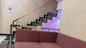 Una habitación con una mesa de madera, un sofá rojo y una escalera al fondo.