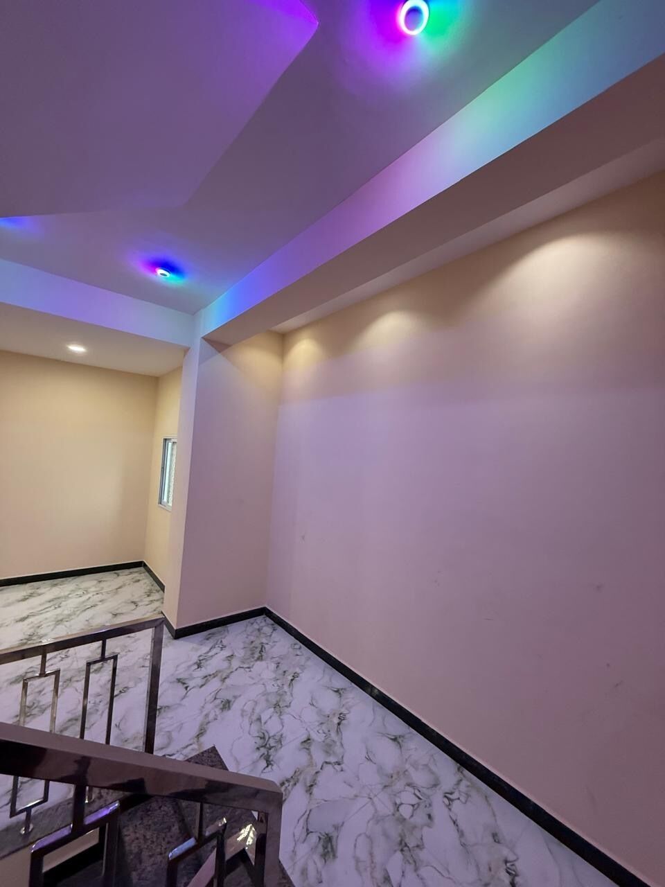 A room with a marble floor, a staircase, and a ceiling with recessed lighting.