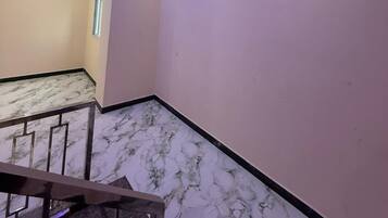 Um quarto com piso de mármore, uma escada e um teto com iluminação embutida.