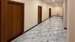 Un pasillo con puertas de madera y suelo de mármol.