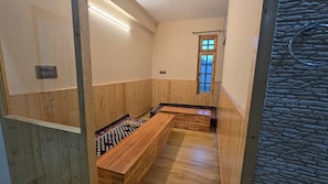 A room with wooden panel walls, a stone accent wall, a window, and a bench. - Rajguru Guest House (Ujjain)