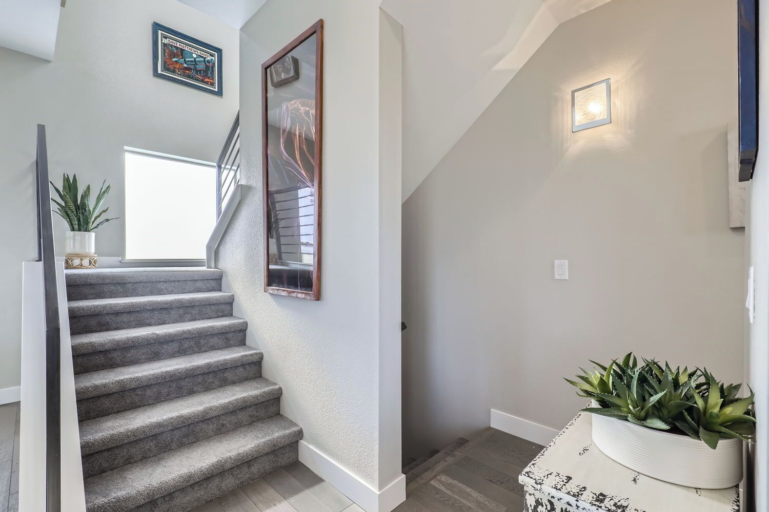 Eine Treppe mit Geländer, einem Blumentopf und einem gerahmten Bild an der Wand.