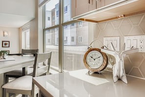 A modern kitchen with a large window, a wooden clock, and a white countertop. - Arvada Townhome | Quiet Location | Fireplace (Arvada)