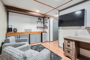 A compact living space with a kitchenette, a sofa, a TV, and a bar area. - 3BR Westminster Home with Hot Tub, Yard + King Suite (Westminster)