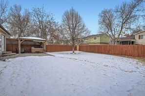 A backyard with a wooden deck, a covered patio, and a snow-covered lawn. - 3BR Westminster Home with Hot Tub, Yard + King Suite (Westminster)
