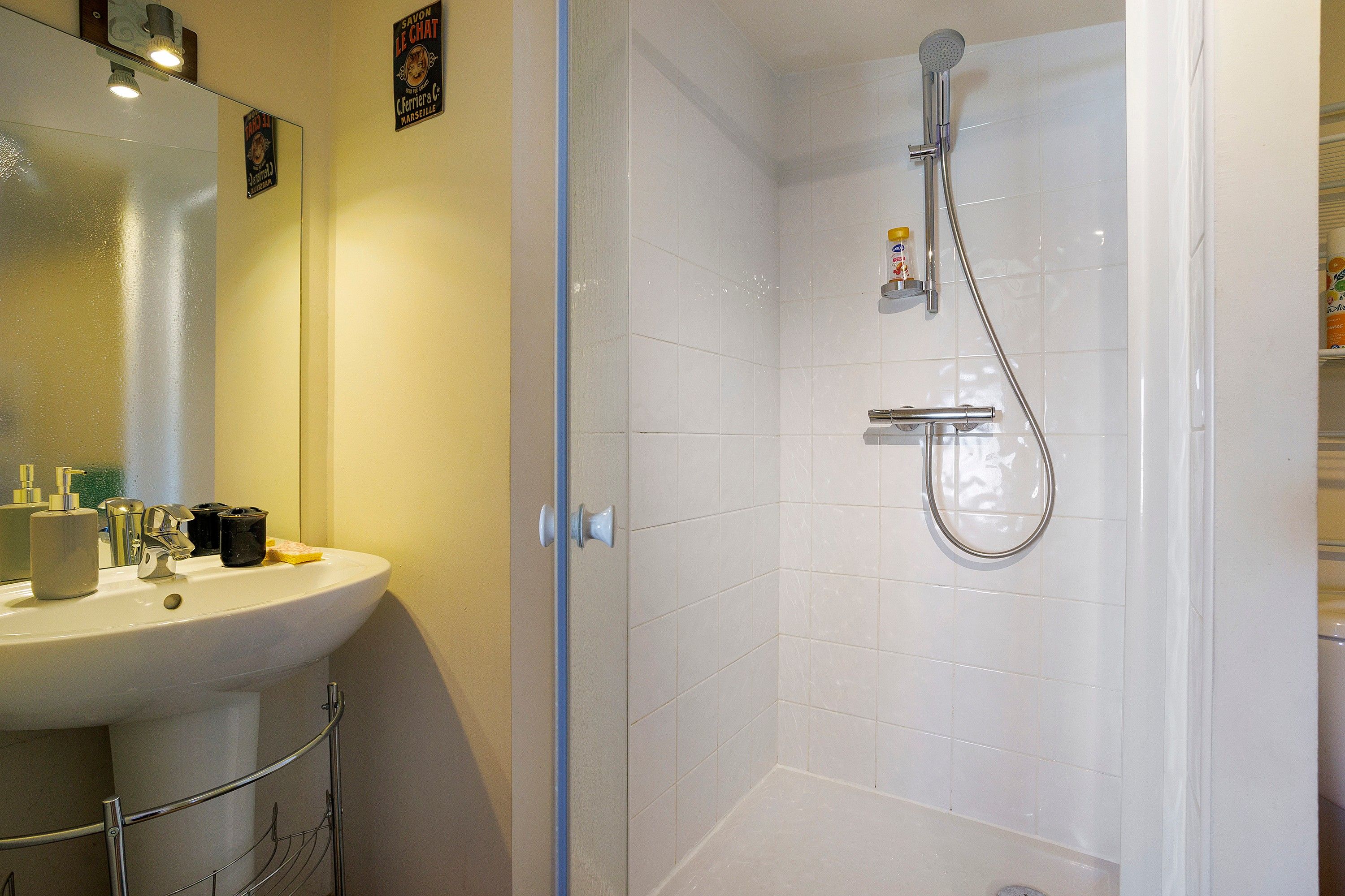 Een badkamer met een witte wastafel, spiegel en douche.