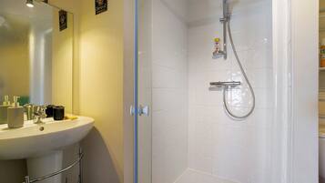 Een badkamer met een witte wastafel, spiegel en douche.