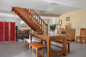 A wooden staircase leading to an upper floor, a dining table with benches, a potted plant, and a lamp on the table. - Cottage 'Gîte Les Hirondelles' with Shared Pool, Private Terrace and Wi-Fi (La Devise)