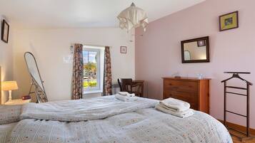 Een slaapkamer met een bed, een dressoir, een spiegel en een hangende lamp.