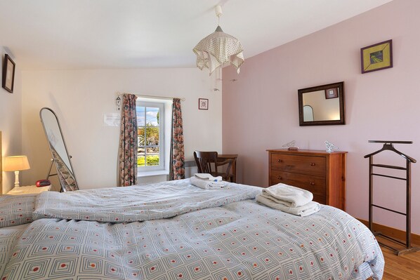 A bedroom with a bed, a dresser, a mirror, and a hanging light fixture.