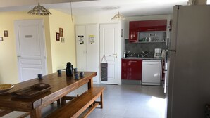 A kitchen with a wooden table, benches, a refrigerator, and red cabinets.