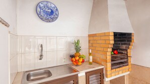 A kitchen with a brick oven, a fruit bowl, and a blue plate on the wall. - Elegant villa with pool in Galé (Albufeira)