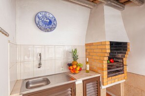 Uma cozinha com forno de tijolos, uma fruteira e um prato azul na parede.