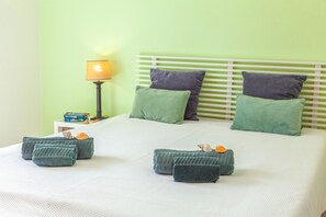 A neatly made bed with green and gray pillows, a white headboard, and a bedside table with a lamp and a box of tissues. - Elegant villa with pool in Galé (Albufeira)